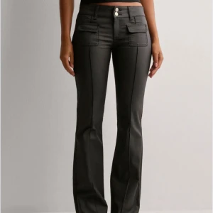 Svarta skinn bootcut byxor  - Snygga svarta bootcut-byxor med markerade sömmar, två framfickor med lock och dubbla silvriga knappar i midjan. Passar fint till vardags eller fest! Stl 38