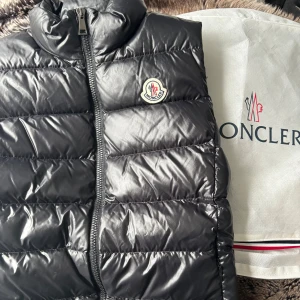 Svart dunväst från Moncler - Säljer en svart dunväst från Moncler med klassisk logotyp på bröstet och dragkedja framtåt. Köpte ny förra året, som nyskick