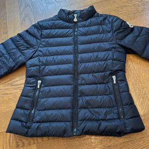 Moncler Jacka - En Moncler jacka i barnstorlek 12/152cm, har använts en säsong men är i väldigt bra skick. Jag säljer då den inte passar längre. Det är en tjej modell så den är lite utsvängd där nere. Köptes för 5299kr på NK (kolla skvittot) och säljs för 2499kr. Om du har några frågor eller vill ha fler bilder så är det bara att skriva till mig! 
