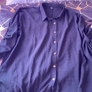 Mörkblå skjorta med träknappar - Säljer en stilren mörkblå skjorta med klassisk krage och långa ärmar. Skjortan har en avslappnad passform och är försedd med snygga träfärgade knappar framtill. Priset är inte hugget i sten! 