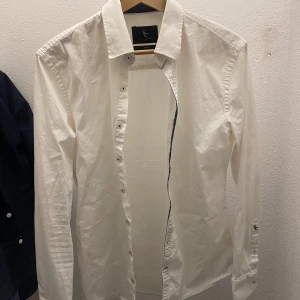 Vit skjorta från Savvy Citizen - Klassisk vit skjorta från Savvy Citizen i storlek Small. Skjortan har lång ärm, knappar framtill och en stilren krage. Perfekt för en clean och enkel look. Tillverkad i bomull för en skön känsla.