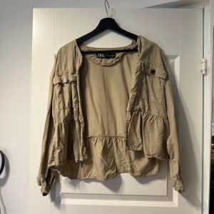 Beige overshirt från ZARA - Säljer en beige overshirt från ZARA med avslappnad passform. Jackan har långa ärmar, stora fickor framtill och knappar som detalj. Perfekt att slänga över en t-shirt för en cool lager-på-lager-look.