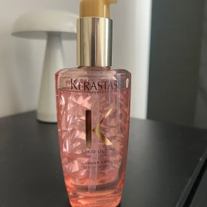 Kérastase Elixir Ultime L'Huile Rose - Lyxig rosa olja i pumpflaska från Kérastase, Elixir Ultime L'Huile Rose. Flaskan har ett elegant mönster och guldiga detaljer. Perfekt för att ge glans och näring till håret.