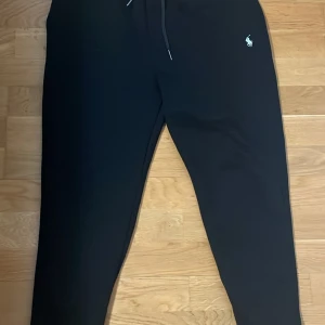 Ralph lauren mjukisbyxor - Svarta mjukisbyxor från Polo Ralph Lauren med dragsko i midjan och broderad logga på ena benet. Byxorna har en normal passform och är perfekta för en avslappnad stil.