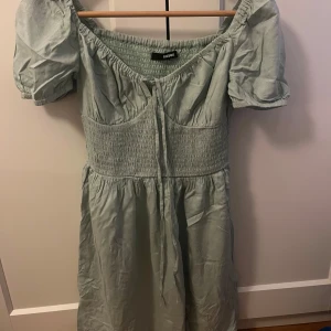 Ljusgrön klänning med puffärm från BikBok - Supersöt ljusgrön klänning från BikBok med puffärmar. Klänningen har knyt framtill. Perfekt för vår och sommar!