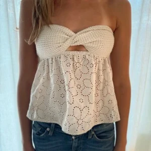 Axelbandslös topp med virkad överdel - Söt axelbandslös topp i beige med virkad twistad överdel och broderade blommor på den vida nederdelen