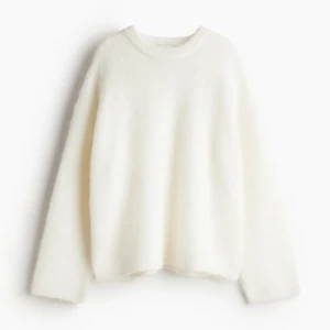 Vit stickad tröja - Mysig vit stickad tröja med rund halsringning och långa ärmar. Perfekt för kyliga dagar och enkel att matcha med olika outfits. Tröjan har en klassisk och stilren design.