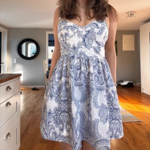 Jätte fin vit och blå kortklänning från Zara!🫰🏻❤️ - Superfin kortklänning i vitt och blått med paisleyinspirerat mönster. Köpt för 599kr och nu är den slutsåld på Zara!! Säljer den för 340! Klänningen har smala axelband, markerad midja och lätt utställd kjol. Perfekt för varma dagar och somriga tillfällen.