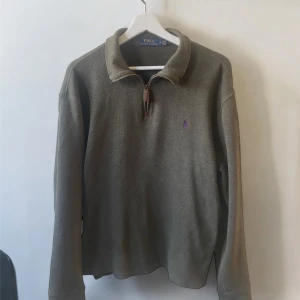 Stickad Polo Ralph Lauren - Säljer en olivgrön långärmad tröja från Polo Ralph Lauren med halv dragkedja och klassisk krage. Liten broderad logga på bröstet. Perfekt för en stilren och avslappnad look. Hör av er vid intresse 