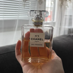 Chanel N°5 Eau Première Eau de Parfum - Elegant parfym från Chanel, N°5 Eau Première. Flaskan är rektangulär med tydlig etikett och klassisk transparent design. Innehåller 100 ml och har en exklusiv, kristalliknande kork. Doften är en modern tolkning av den ikoniska Chanel N°5.