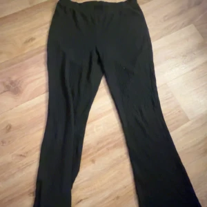 Svarta ribbade byxor - Svarta ribbade byxor med elastisk midja och raka ben. Byxorna har en bekväm passform och är perfekta för en avslappnad stil. Materialet är mjukt och stretchigt vilket gör dem sköna att bära hela dagen.