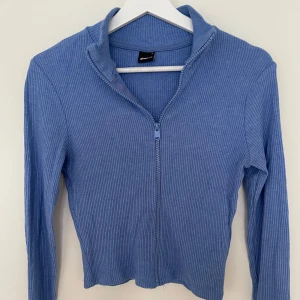 Blå ribbad tröja från Gina Tricot - Säljer en blå ribbad tröja från Gina Tricot i storlek M. Tröjan har dragkedja framtill, lång ärm och är tillverkad i ett mjukt, stretchigt material. Använd fåtal gånger som ny