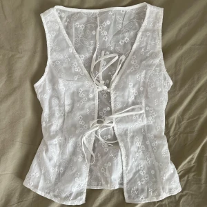 Vit topp med knytband - En söt, vit linnetopp med blommor som är perfekt till sommaren. Knytband där fram. Köptes second men säljs då den är för liten för mig:( Den är från Zara, storlek S (men passar bra på xs också). Skriv gärna om ni har frågor!🤗
