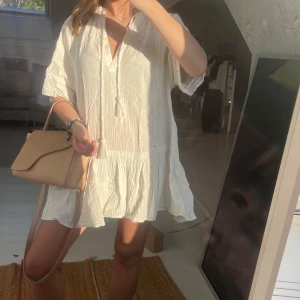 Gullig klänning  - Säljer en luftig och söt vit kortklänning med volangkant och knytband framtill🥰