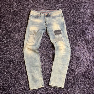Ljusblå jeans med patch-detaljer från Free Side - Säljer ett par ljusblå jeans från Free Side med unika patchade detaljer och slitningar på framsidan. Jeansen har raka ben och klassisk femficksdesign. Perfekt för dig som vill sticka ut med din stil. Hör av dig vid minsta fundering🙌
