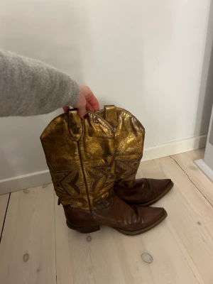 Brunguldiga cowboystövlar  - Bruna äderstövlar med gulddetaljer och klack 