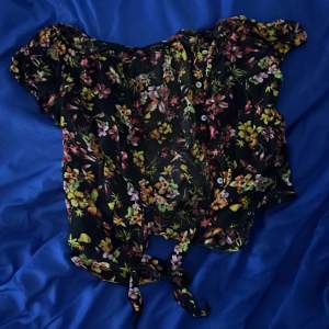 Blommig skjorta med korta ärmar och knytning längs ner på skjortan