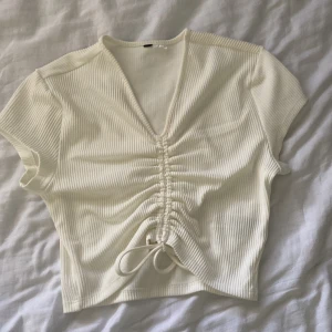 Tröja med detalj  - Kortärmad tight tröja med snörning i mitten. V-ringad, knappt använd.  Storlek Xs-S