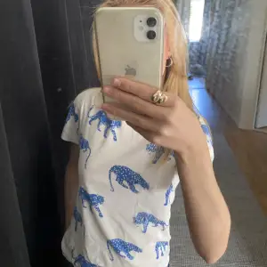 En vit t-shirt från H&M med olika blåa kattdjur som tryck. Bra skick men för liten för mig🫶🏼