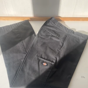 Dickies byxor - Ett par dickies skate-byxor med dubbelt tyg på knäna. De har även en ficka på sidan av låret på höger sida. De är förlängda längst ner men det har börjat slita sig som man ser på tredje bilden. Annars fint skick. Pris kan variera. 