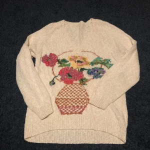 Stickad tröja  - Stickad tröja med vas och blommor på, knappt använd, skönt inte stickigt material, ganska tunn så kan ha den året runt;k)