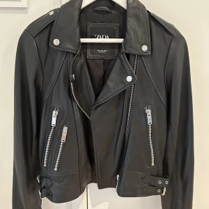 Bikerjacka skinn - ZARA WOMAN COLLECTION  Bikerjacka i 100 % skinn.  Långärmad. Öppningar i ärmsluten. Framfickor. Knäppning fram med metalldragkedja. Nypris: 2500 Stl: S ( normal i stl ) regularfit  Har använt Max 2 ggr, helt ny Svart! (Liknar Acne jackan )