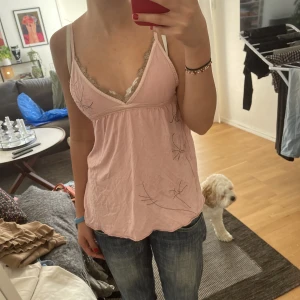 Linne - Fint och gulligt rosa linne med fina spetsdetaljer. Har även blommgrenar på bröstet och ena sidan. Super gullig!