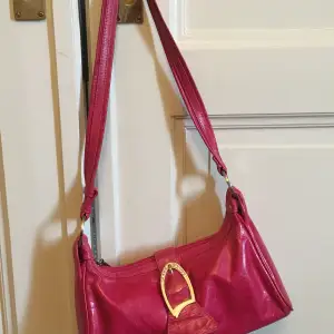 Elegant liten handväska i rosa läder.  Storlek: ca 30 x 15 x 9,5 cm.  Handtaget: ca. 36 cm i höjden. Material: läder  Tillverkningsland: Italien 