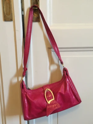 Handväska i skinn Italien - Elegant liten handväska i rosa läder.  Storlek: ca 30 x 15 x 9,5 cm.  Handtaget: ca. 36 cm i höjden. Material: läder  Tillverkningsland: Italien 