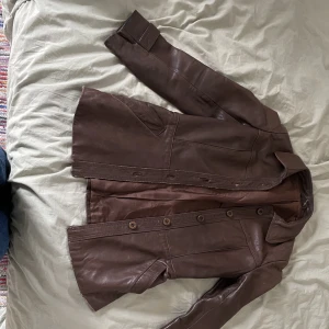 Läderjacka - Brun läderjacka, köpt secondhand. Sliten vid knapparna där fram, det syns alltså att den använts tidigare.Tjockare i materialet och håller värmen, så en jättebra höstjacka! 😌  