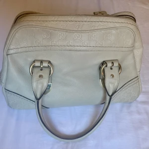 Gucci, vit skinnvästs, handväska, guccissima - Fin, äkta Gucciväska i vitt läder med guldfärgade detaljer. Köpt på Gucci i Stockholm på tidigt 2000-tal, men sparsamt använd. Finns även bild på baksidan av taggen där man kan se en del av siffrorna (men de är lite fadeade eftersom den är ca 20år gammal)