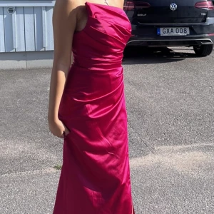 Festklänning  - En lång klänning gjord av satin, med en lång slit. Väldig elegant. En Barbie klänning!  Kan sälja billigare om det är snabbköp. Ni får även me klänningenspåse! (Använd 1 gång)