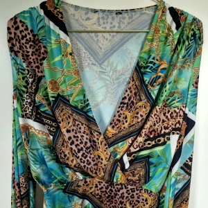 Mönstrad omlott body i härliga färger - OANVÄND! Säljer denna body från Nelly i starka vackra färger - perfekt till sommaren eller solsemester. Stringbody i härligt material som sitter smickrande på kroppen. Passar både en XS och en S. 