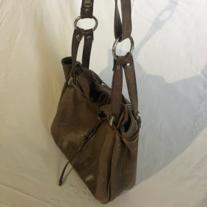 Brun axelremsväska i läder - En så fin väska i äkta läder med väldigt fina detaljer! Så bra till vardags och rymmer mycket👌