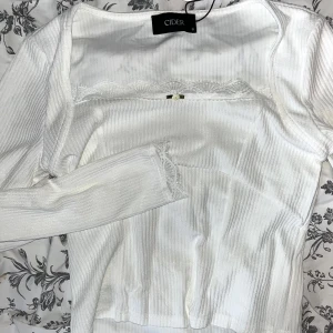 Vit tröja - Säljes då den inte används 🤍 Vit långarmad topp från cider med fina spets detaljer🐚 Aldrig använd, original lapp och påse finns kvar☁️ Bilden på andra sliden är från Ciders hemsida och visar den lila modellen!!(fanns ej bild på den vita) originalpris: 198🤍