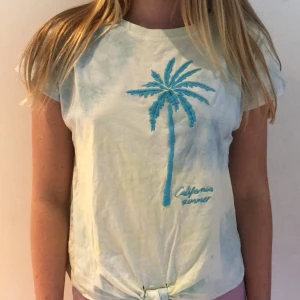 Tie dye teeshirt med knut  - Blå grön tie dye teeshirt med knut och en Palm på. Det står också carlrfonia summer på den. Kontakta privat för fler bilder. 