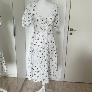 Blommig klänning - En jättefin klänning med knappar och blommigt mönster till salu. Använt en gång men är tvättad och  ren. Köpt från Spanien. Jättefin passform.