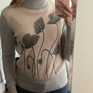 Grå-rosa stickad tröja med polokrage - Supersöt stickad rosa-grå tröja med polokrage och stickad pärlor på blommdetaljerna. Begagnat skick, men inga fläckar eller hål! Passar XS-M🫶💕