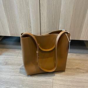 Beige/brun väska från NA-KD. Perfekt till jobbet eller skolan då den är väldigt rymlig, har även ett inbyggt gfack/necessär i väskan, Aldrig använd, slutsåld på hemsidan i nuläget. Nypris 449kr, mitt pris 250kr+frakt :)