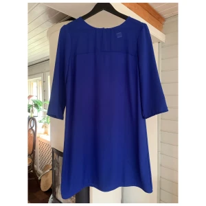 Blå klänning med meshdetalj - Blå långärmad klänning med meshdetalj upptill. Storlek 40, oanvänd.