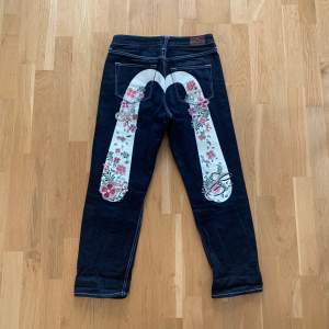 Väldigt unika Evisu Heritage jeans med lite sprickor i vita färgen, annars inga defekter på de broderade blommorna, stitching elr resten av byxorna.