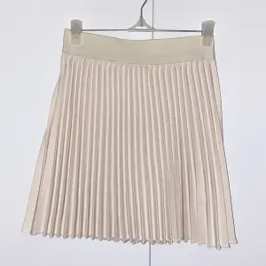 Fin kort vecklad kjol i beige/ljusrosa som inte kommit till användning, aldrig använd! 💞