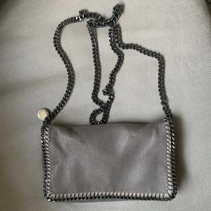 Stella McCartney Falabella väska grå  - Crossbody-väska från Stella McCartney i använt men superfint skick. Köpt för ca. 7000kr runt år 2016. Gör vilken outfit som helst classy! 