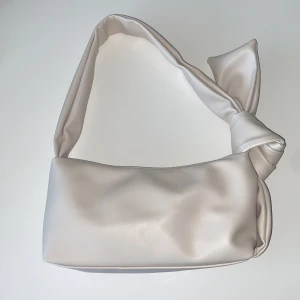 Hand/axelväska i faux skinn  - Väskan är aldrig använd och i fint skick med rosett vid ena sidan som rymmer mycket.