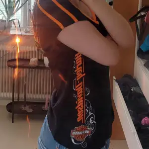 Super snygg ÄKTA harly davidson t-shirt med oranga och vita detaljer. Den har små defekter på texten men inget stort, v neck och lite off shoulder, Super strechig och extremt bäkväm, säljs pga av att jag inte passar i orange, läs bioo!!!!