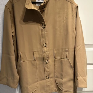 Kavaj/blus - Brun/beige kavaj, blus.  Tillhörande bälte medföljer som är i samma färg. 