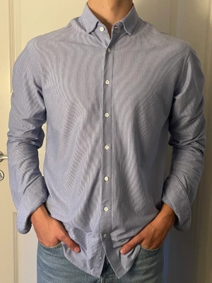 Märkesskjorta, Dressman  - Bekväm och fin märkesskjorta säljes med stor rabatt från orginalpris. Perfekt för såväl daglig användning som finare tillfällen.  Nypris 699kr  Randig skjorta Blå/vit 