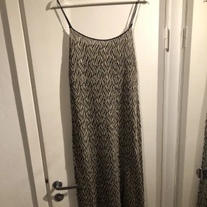 Glittrig zebraklänning  - Lång glittrig zebramönstrad klänning med slits. Knappt använd och i bra skick. 