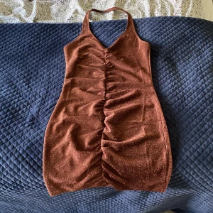 Glittrig halterklänning - Brun glittrig halterklänning från hm strl S. Använd en gång, skicket är som ny. 