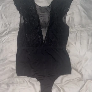 Spets body - En festlig body från pieces (Vero Moda) med spets framtill och med mesh och öppen rygg baktill!  Passar en xs/s